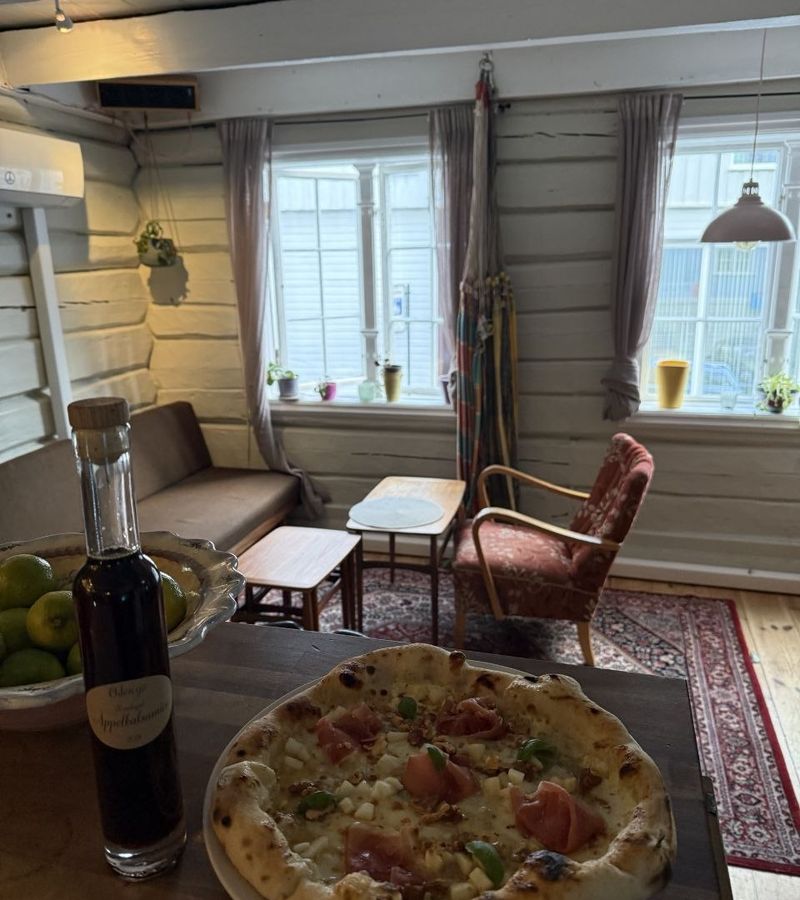 Pizza på disken foran sofakroken og vinduene på Kambuzi
